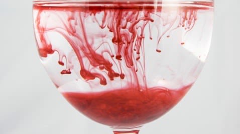 Red fluid spreading within a wine glass