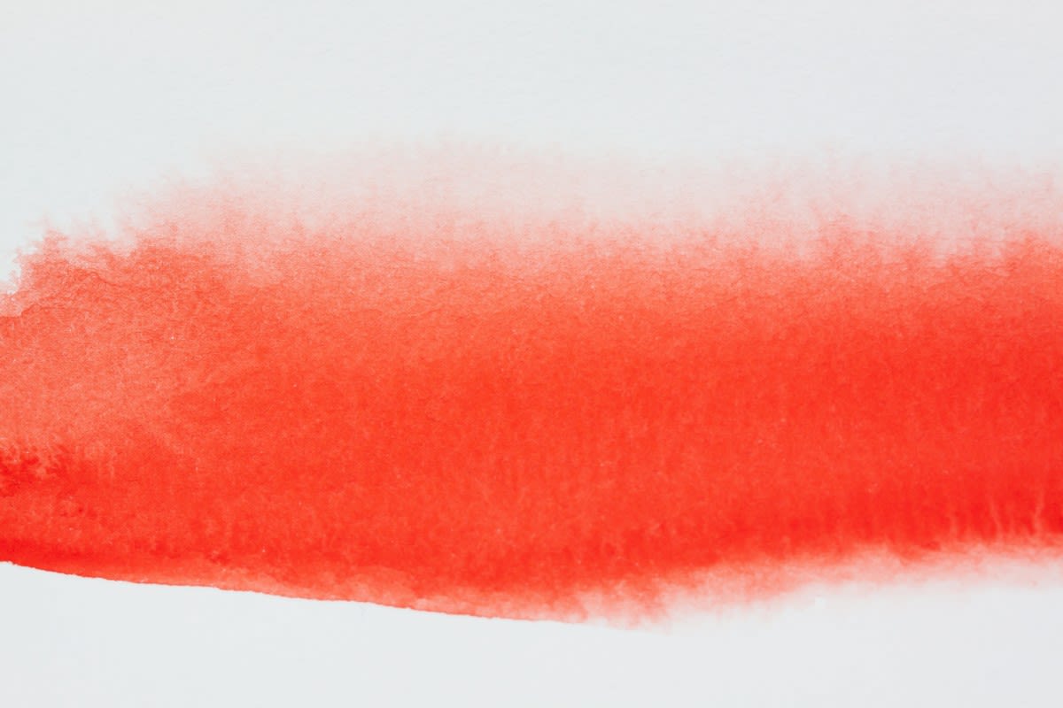 Reddish fluid spreading against white background